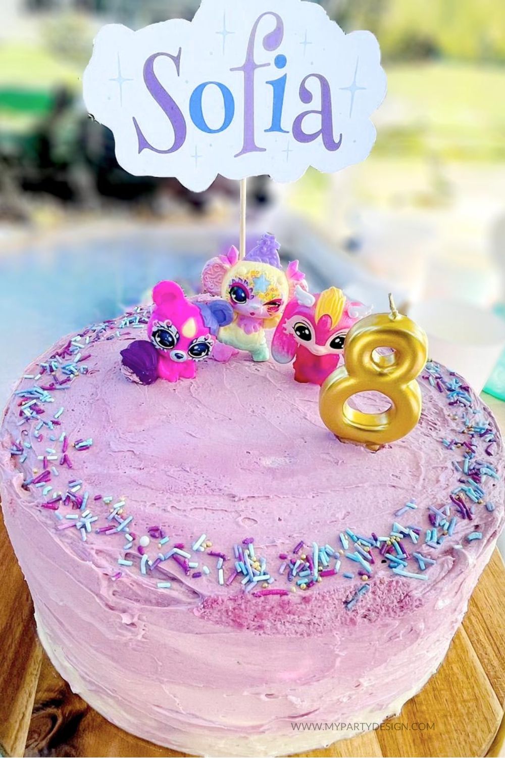 birthday cake with purple frosting with magic mixies figurines and golden candle