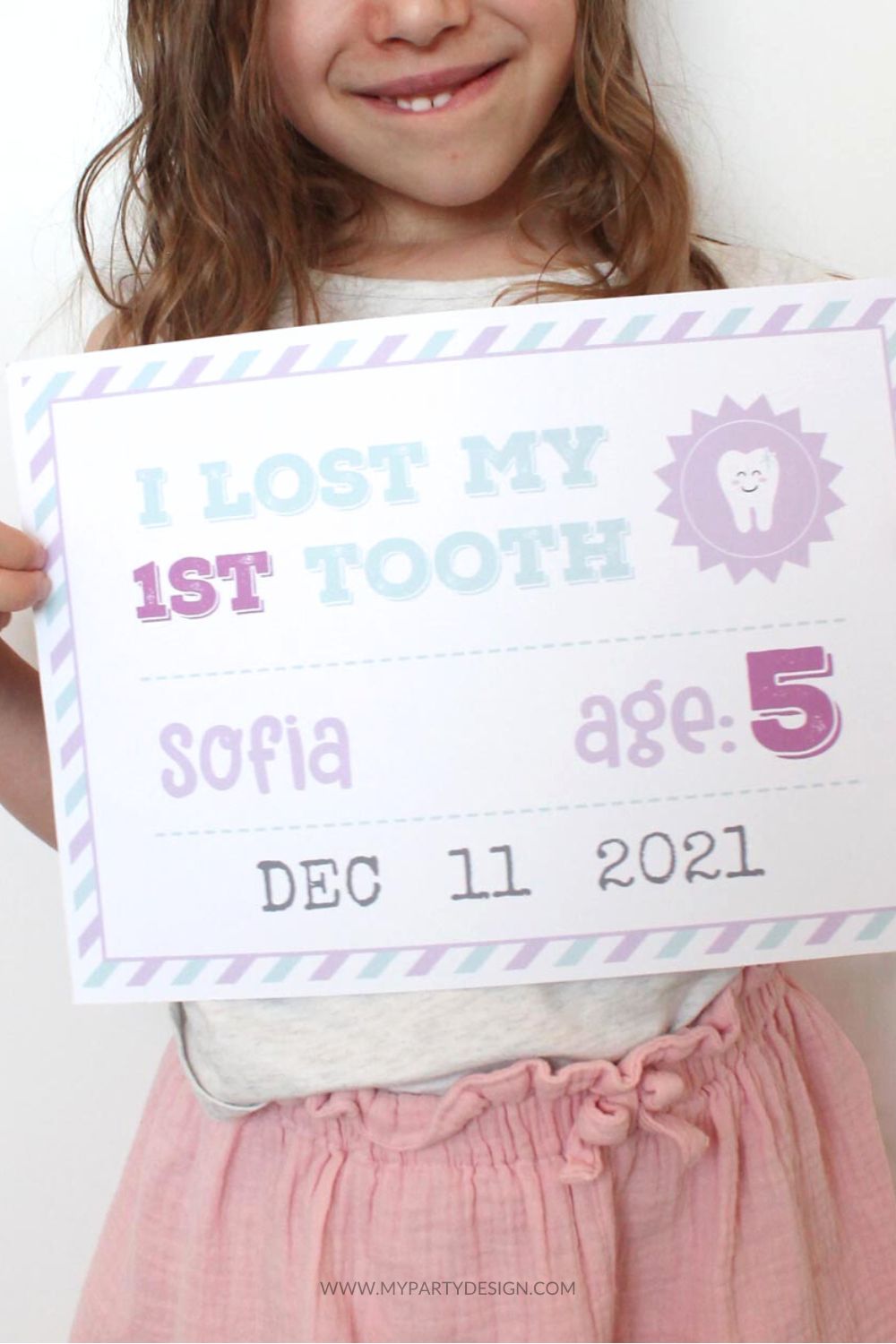 little girl holding milestone sign that reads "I lost my first tooth" 
